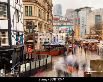 Manchester Christmas Markets in Exchange Square. Blurred figures on a wet day in Manchester City centre. Stock Photo