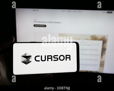 Stuttgart, Germany - 12-03-2025: Person holding smartphone with logo of ai software company Cursor (Anysphere Inc.) on screen in front of website. Stock Photo