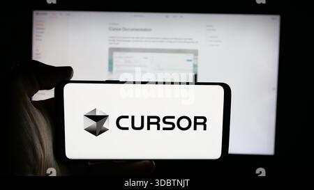 Stuttgart, Germany - 12-03-2025: Person holding cellphone with logo of ai software company Cursor (Anysphere Inc.) on screen in front of webpage. Stock Photo