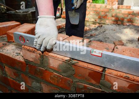 Bricklayer Using Spirit Level While Building Brick Wall Stock Photo