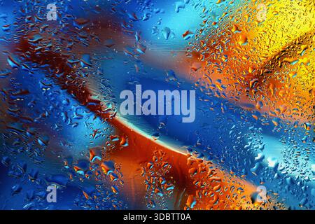 Water droplets on glass surface with abstract blend of blue, orange and yellow hues. Liquid motion, artistic texture, vibrant modern color Stock Photo