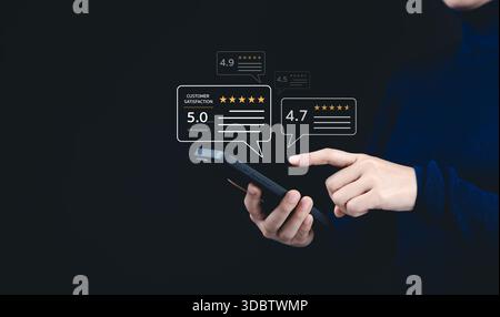 Customer review satisfaction feedback survey concept. A woman interacts with a smartphone, giving a five-star rating using a digital feedback system, Stock Photo