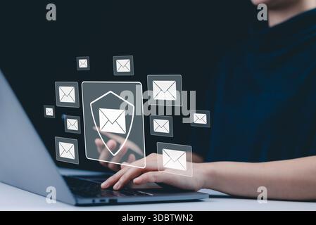 Email security and protection technology concept. A woman using a laptop and phone, with virtual email icons and shield symbolizing data security and Stock Photo