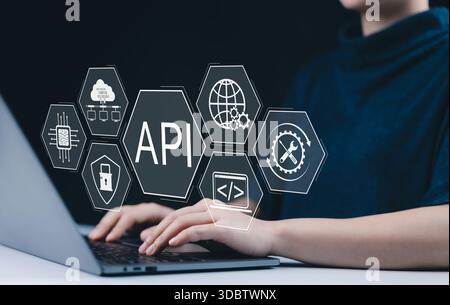 API Application Programming Interface Concept. A person types on laptop, with digital icons representing API development, security, and cloud computin Stock Photo