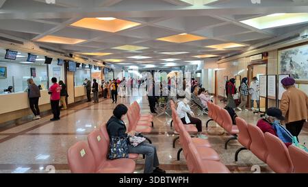 Taipei, Taiwan, December 18, 2025. Patients wait in the hospital reception area with service counters and digital queue displays Stock Photo