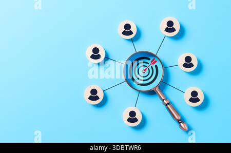 CRM, Customer Relationship Management and Target Audience Concept. A magnifying glass focusing on a target with interconnected wooden icons representi Stock Photo