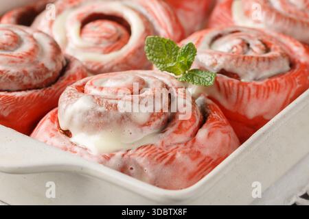 Homemade pink cinnamon rolls with cream cheese in a baking dish on the table. Horizontal Stock Photo