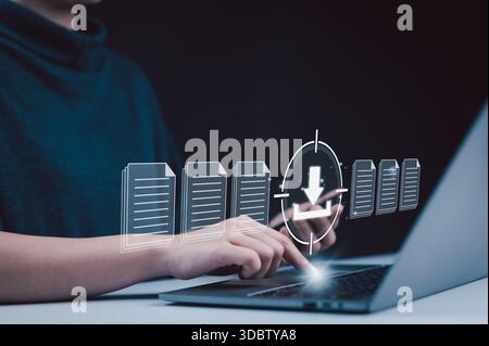 File download and data transfer technology concept. Woman using laptop and smartphone with digital file icons and download symbol, representing modern Stock Photo
