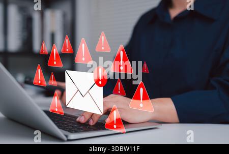 Email security threat and spam warning concept. Person using laptop with red warning icons and envelope representing email threats, phishing, spam Stock Photo