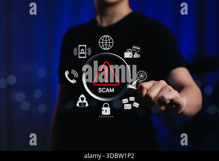 Scam Alert and Cybersecurity Threat Detection Concept. Person holding magnifying glass with scam warning icon, online threats, phishing cyber security Stock Photo