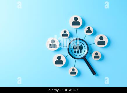 Magnifying glass focusing on target customer group with human icons on blue background, representing business marketing, audience analysis, customer Stock Photo