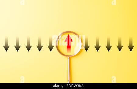 Thinking differently and finding new perspectives. Magnifying glass focuses on a red upward arrow among black downward arrows, innovation, leadership, Stock Photo