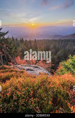 View of the sun rising over the forest, casting a golden glow on the treetops and the vibrant autumn colors below, Polana, Banska Bystrica Region, Slo Stock Photo