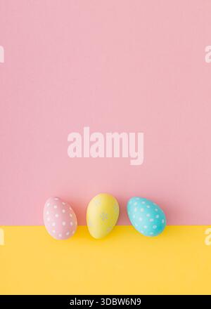 Spring composition with colorful Easter eggs on pastel pink and yellow background. Creative Easter concept. Festive holiday layout. Flat lay. Stock Photo
