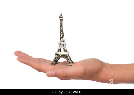 Hand holding a mini Eiffel tower souvenir figurine from Paris, France, metaliic miniature statue isolated on white backround, cut out Stock Photo