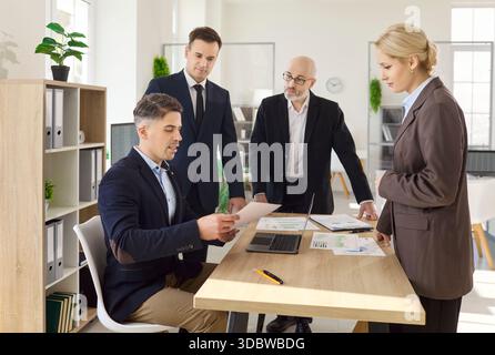 Business team meeting at desk, reviewing reports and planning strategy together Stock Photo