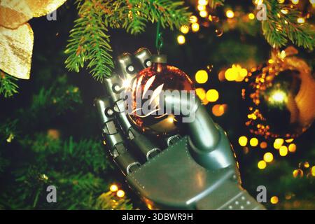 Futuristic Christmas tree with a humanoid robot hand holding a shiny and glitter futuristic black ornament with blue light and circuit print putting i Stock Photo