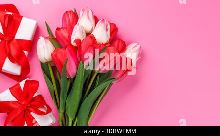 Pink tulip bouquet and gift boxes on a soft pink background, perfect romantic or springtime greeting concept Stock Photo