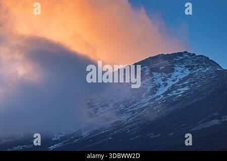 Slavkovsky peak in High Tatras National Park, Slovakia, Europe. A tranquil mountain peak shrouded in mist under a vibrant sky, where nature's artistry Stock Photo