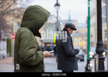 People using smartphones on a street. Woman and man in winter city Stock Photo