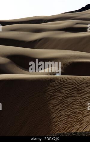 View of rippling waves of sand dunes, sculpted by wind, create a mesmerizing pattern of light and shadow across the desert landscape, Noshki, Balochis Stock Photo
