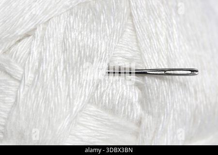 Sewing Needle with White Wool Yarn, Close-Up on White Background Stock Photo