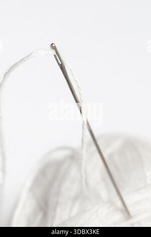 Sewing Needle with White Wool Yarn, Close-Up on White Background Stock Photo