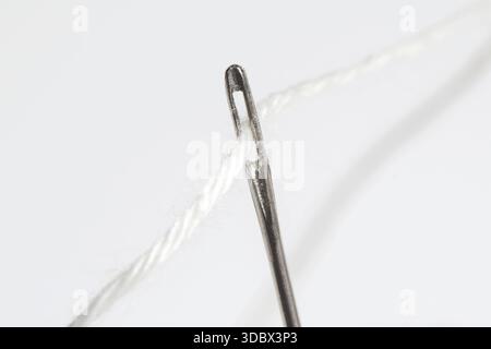 Sewing Needle with White Wool Yarn, Close-Up on White Background Stock Photo