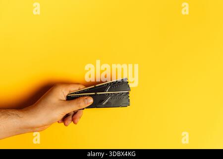 Hand presenting stack of desktop RAM modules on yellow background Stock Photo