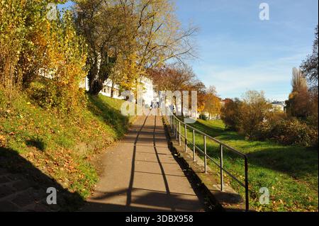 Pforzheim, Germany Dezember Ascending sunlit suburban path with railing and long shadows, gentle incline, grassy banks, clear sky, Stock Photo
