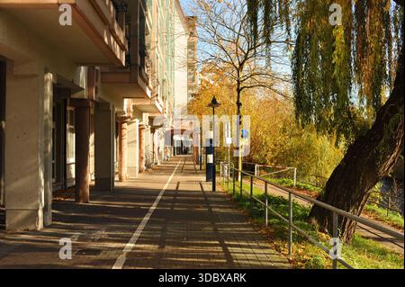 Pforzheim, Germany Dezember Sunlit urban walkway lined with shops, warm shadows, lamppost accents, autumn leaves on pavement, Stock Photo