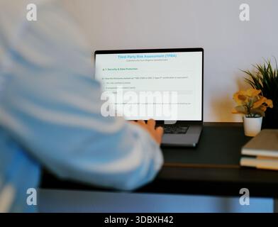 Middle Aged Male Cybersecurity Analyst Conducts Third Party Risk Assessment on Outside Vendor Stock Photo