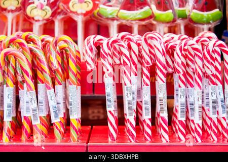 Tallinn, Estonia - December 03, 2025: Candy canes in red and white stripes, yellow and orange stripes, arranged in rows on display with colorful lolli Stock Photo