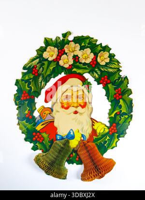 1960s Vintage paper Christmas decoration featuring Santa Claus inside a festive holly wreath with two mesh bells at the bottom Stock Photo