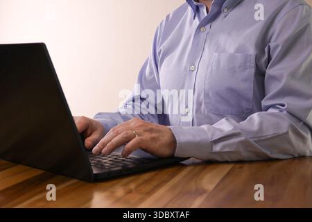 Anonymous Man Typing on Laptop at Wooden Table Stock Photo
