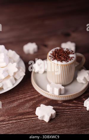 cozy arrangement of coffee cup with brown chocolate sprinkles and star-shaped marshmallows on wooden surface for a warm and inviting culinary experien Stock Photo