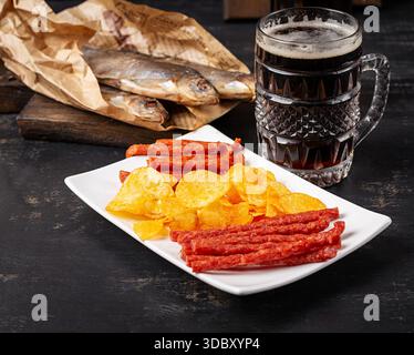 Beer and snack, chips and kabanos on a dark background. Stock Photo