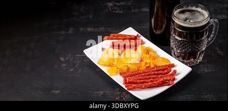 Beer and snack, chips and kabanos on a dark background. Stock Photo