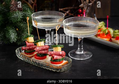 Canapes with salami, cheese, tomato. Christmas and New Year's dishes. Snacks and wine drinks for the holiday table. Stock Photo