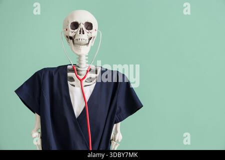 Human skeleton in black medical uniform with stethoscope on turquoise background Stock Photo