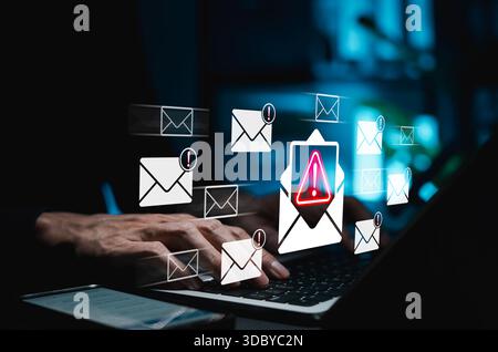 Email phishing alert and cybersecurity threat detection concept. Hands typing on laptop with warning icons and suspicious email Stock Photo