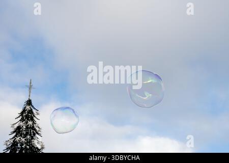 A large soap bubble drifts above historic Lisbon buildings on a clear winter day creating a light colorful reflection in the sky Stock Photo