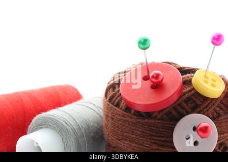 Ball of bright knitting yarn with buttons, spools of thread and pins on white background Stock Photo