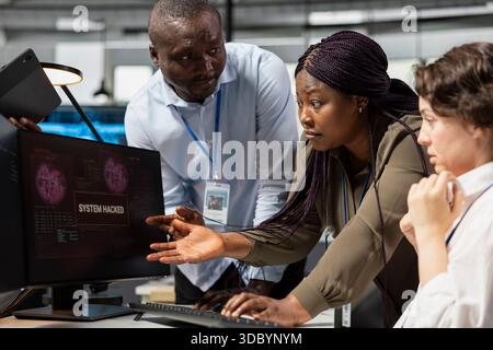 Engineering team in office working together to fix hacking attempt on corporate network. Teamworking IT department colleagues doing brainstorming, investigating unauthorized access alerts Stock Photo