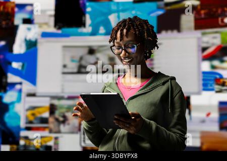 Smiling woman engaging with multimedia dashboards using tablet, showcasing power of technology and digital content. Joyous person having fun interacting with device apps and internet websites Stock Photo