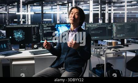 Smiling data center manager filming presentation, showcasing equipment using AI tech. Happy businessman presenting server room built for digital storage systems using artificial intelligence, camera A Stock Photo