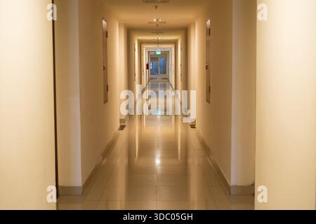 Long Interior Hotel Corridor With Warm Lighting And Reflective Floor Stock Photo
