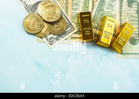 Various forms of currency are displayed on a light blue surface. Gold bars and coins are shown alongside paper bills. The setup allows for clear space Stock Photo