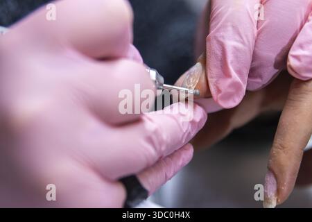 Close-up of a nail technician using a drill on a client's nails at a salon Stock Photo