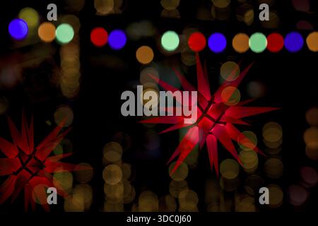 Advent window with numbers, red light stars, glowing Griland stars in red and gold, colored fairy lights hanging, colorful bokeh light circles, advent Stock Photo
